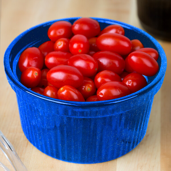 A blue Tablecraft cast aluminum bowl with ridges filled with red cherry tomatoes.