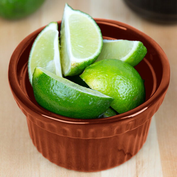 A Tablecraft copper cast aluminum bowl filled with limes on a counter.