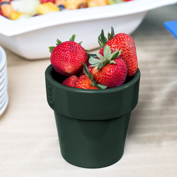 A Tablecraft hunter green cast aluminum round condiment bowl filled with strawberries.