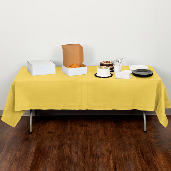 A Mimosa yellow Creative Converting tablecloth on a table with food.