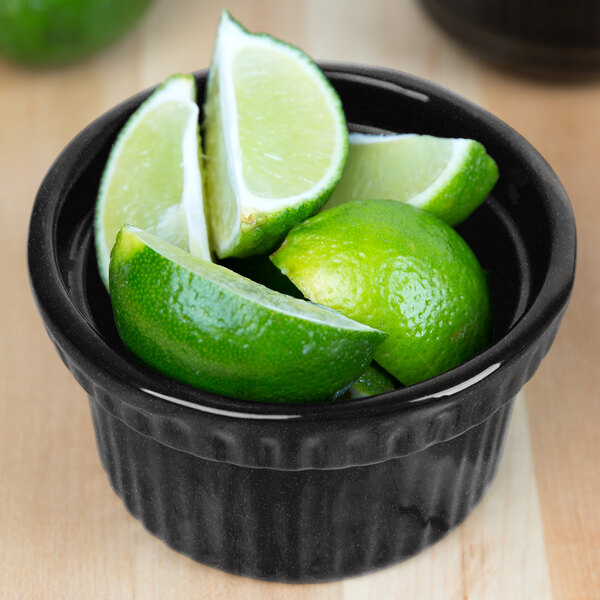 A Tablecraft cast aluminum souffle bowl filled with limes on a counter.