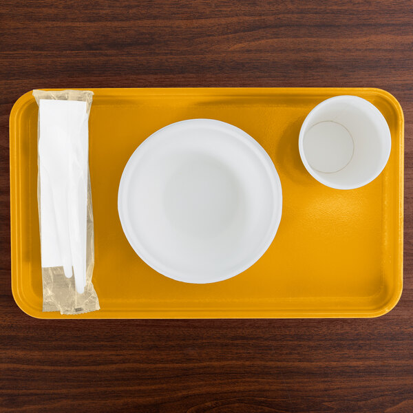 A yellow rectangular Cambro tray with a white bowl and cup on it.