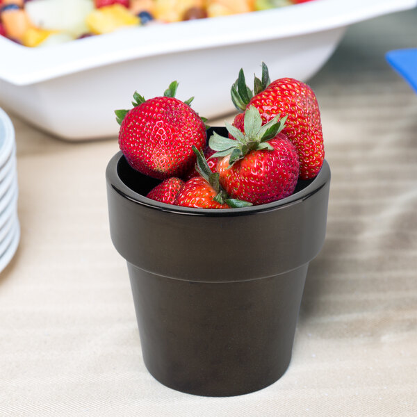A Tablecraft black cast aluminum bowl with strawberries in it.