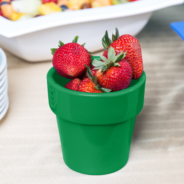 A green Tablecraft round condiment bowl with strawberries in it.