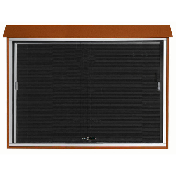 A brown rectangular Aarco message center with a black sliding door.