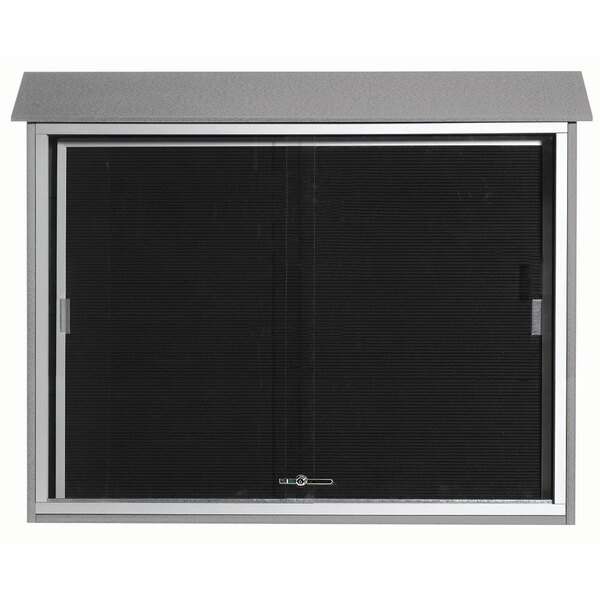 The sliding door of a light gray Aarco outdoor message center with a black and silver window.