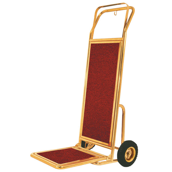 A stainless steel and brass Aarco luggage cart with red carpeting.