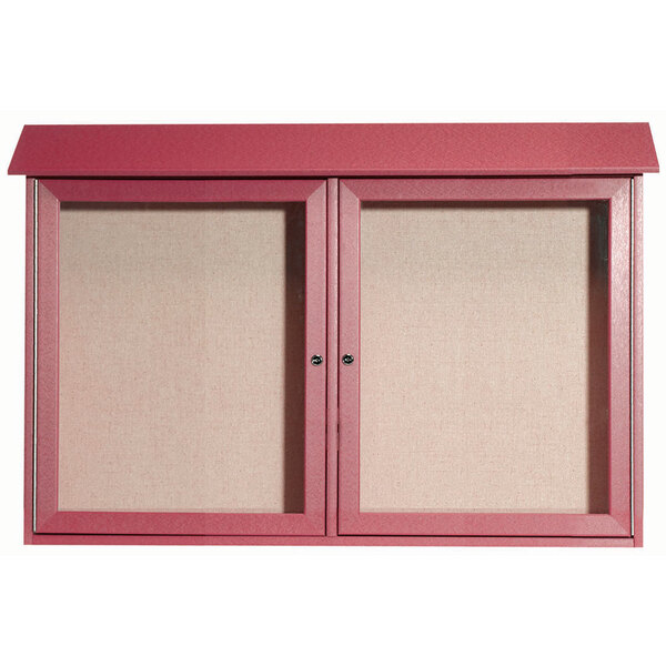 A red rosewood cabinet with two pink vinyl tackboards inside with two doors.
