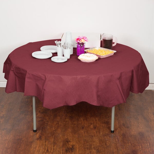 A table with a red Creative Converting OctyRound tablecloth, plates, and food.