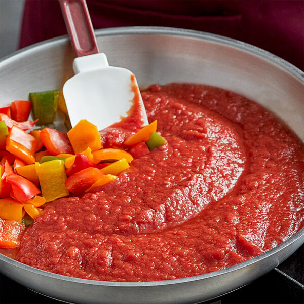 A pan of red sauce and chopped vegetables.