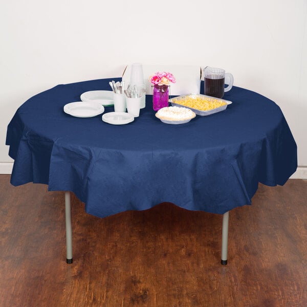A table with a navy blue Creative Converting OctyRound table cover, plates, and food.