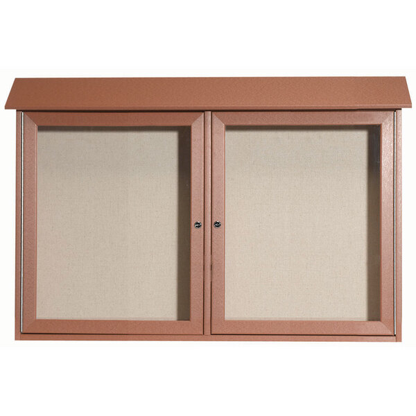 A brown cabinet with dual hinged glass doors enclosing two bulletin boards with vinyl tackboard.