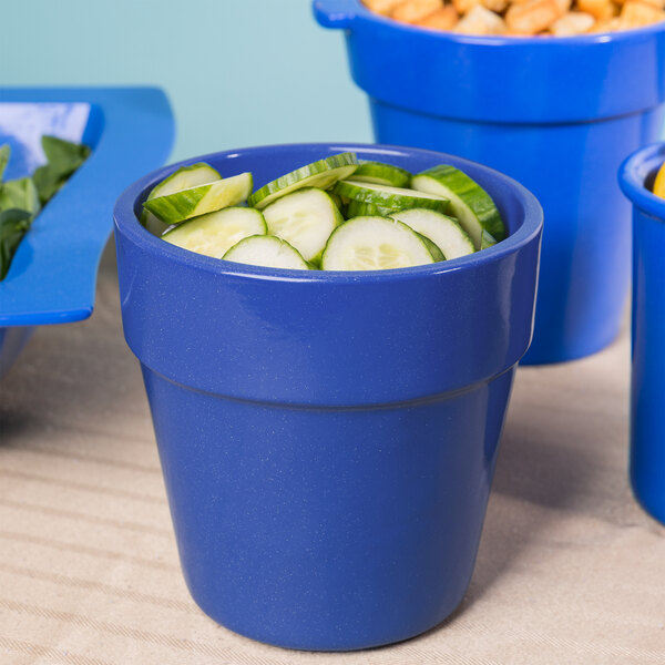 A blue Tablecraft cast aluminum bowl with cucumbers and other vegetables.