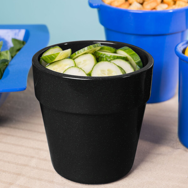 A black Tablecraft condiment bowl full of cucumbers on a table.