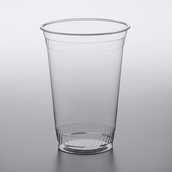 A Fabri-Kal clear plastic cup with a lid on a gray surface.