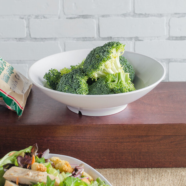 A white Carlisle melamine bowl filled with broccoli on a table.