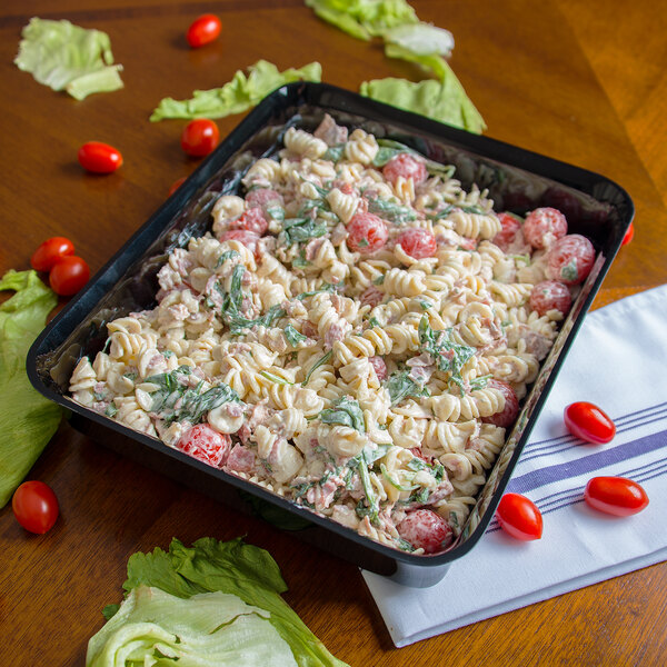 A table with a Carlisle rectangular deli crock filled with pasta salad with tomatoes.