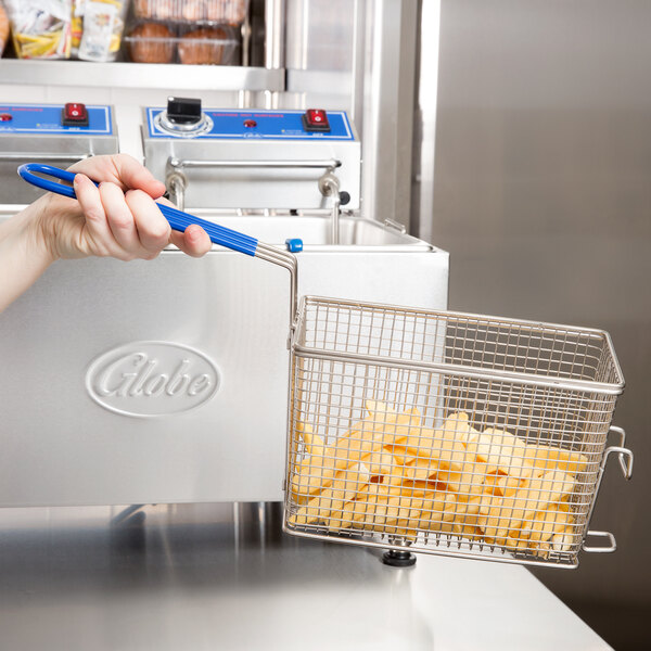 A hand uses a Globe large fryer basket to fry chips.