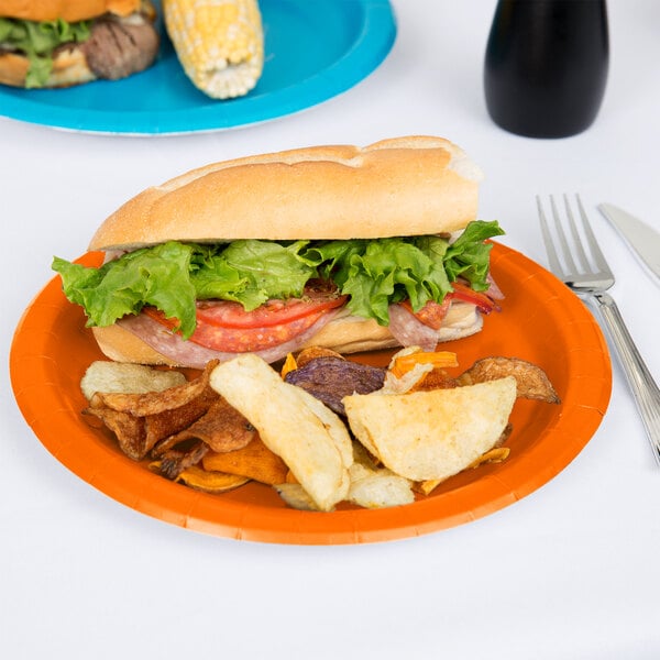 A sandwich and potato chips on a Creative Converting Sunkissed Orange paper plate.
