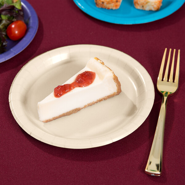 A piece of cheesecake with strawberry jam on an ivory paper plate with a fork.