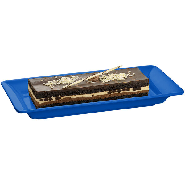A rectangular chocolate cake with white and brown frosting on a blue Tablecraft cast aluminum platter.