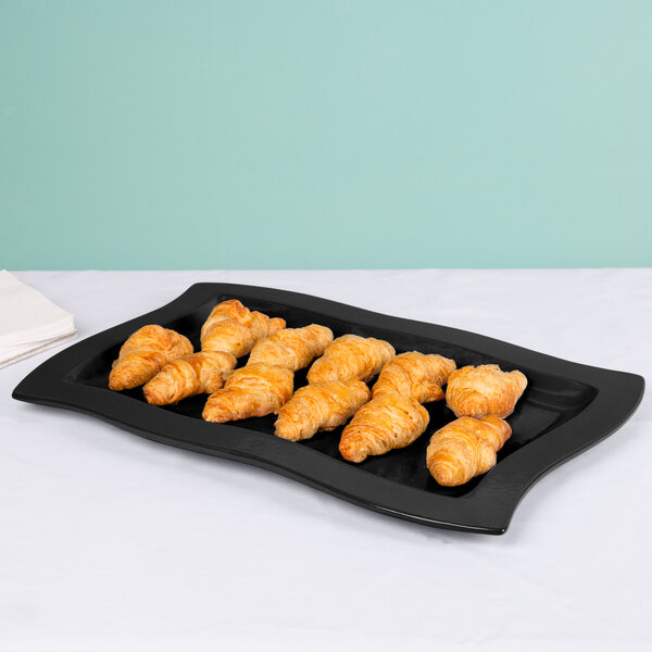 A black Tablecraft rectangular platter with croissants on it.