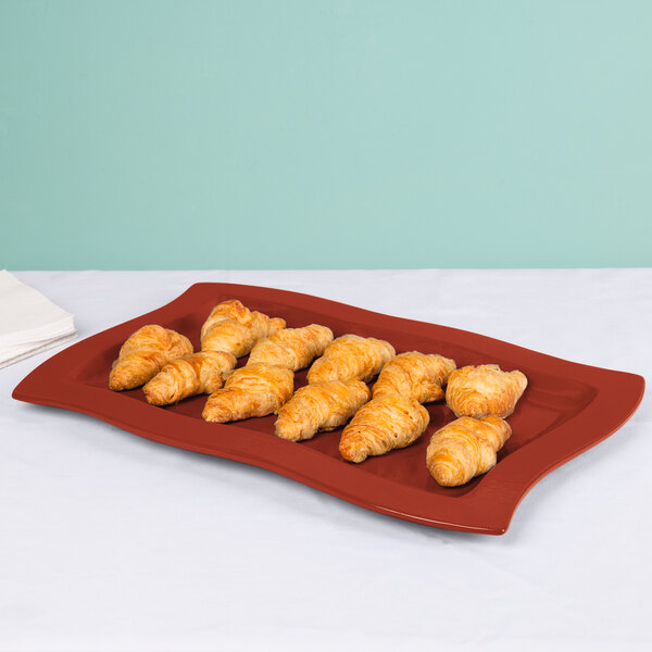 A Tablecraft copper rectangular platter with croissants on a table.