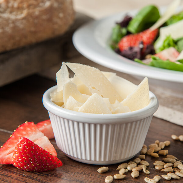 A white Carlisle fluted ramekin filled with cheese next to a salad.