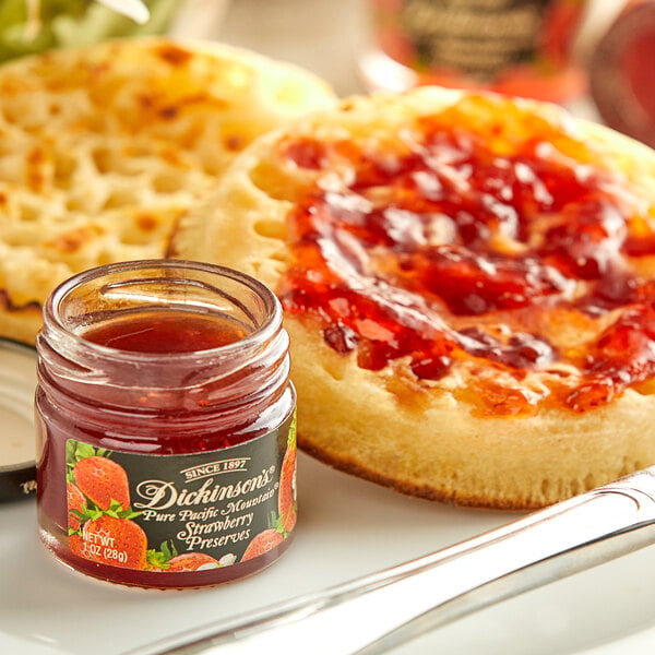 A jar of Dickinson's Pure Pacific Mountain Strawberry Preserves on a table with crumpets and jam.