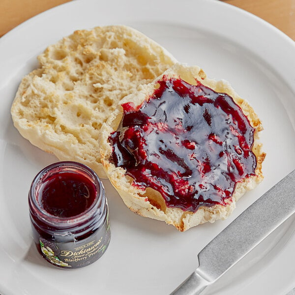 A plate with a biscuit and a jar of Dickinson's Blackberry Preserves on it.