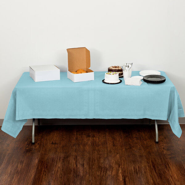 A table with a Creative Converting pastel blue table cover and food on it.