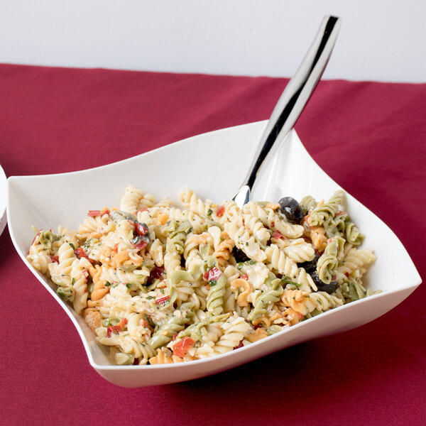 A Fineline ivory plastic serving bowl filled with pasta salad with a spoon and fork.