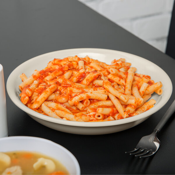 A Diamond Ivory melamine bowl filled with pasta and sauce with a fork.