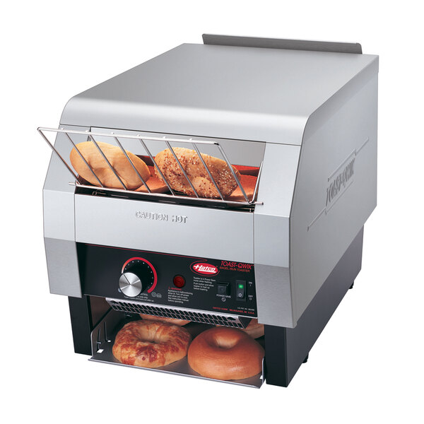 A Hatco conveyor toaster with bagels on it.
