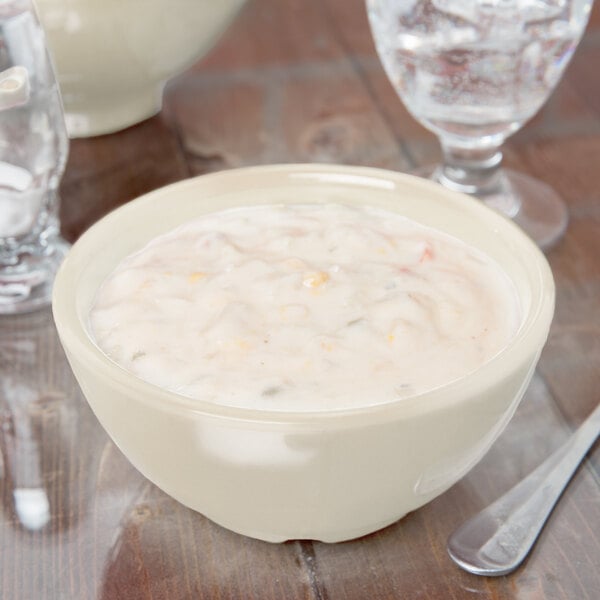 A close-up of a white GET Diamond Ivory bowl of soup on a table.
