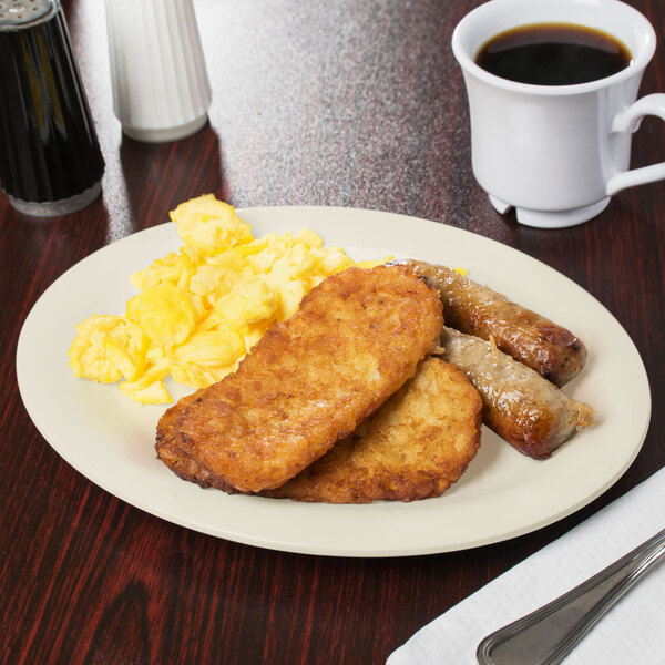 A Diamond Ivory oval platter with eggs, sausage, and toast on a table with a cup of coffee.