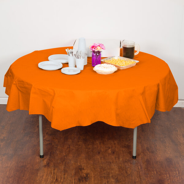 A Sunkissed Orange OctyRound table cover on a table with plates and cups on it.