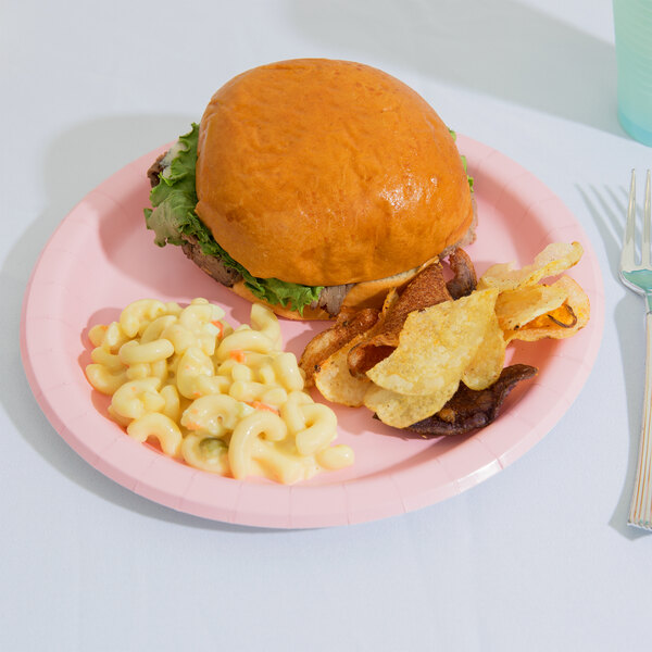 A Classic Pink Creative Converting paper plate with a hamburger, macaroni and cheese, and potato chips on it.