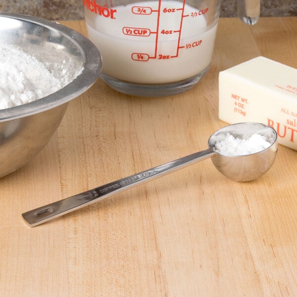 A Tablecraft stainless steel coffee/measuring scoop with a bowl of flour.