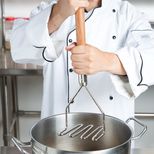 A chef uses a Thunder Group potato masher with a wooden handle to mash potatoes.