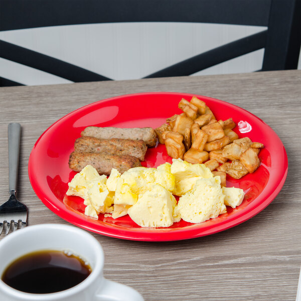 A red Carlisle Sierrus melamine plate with breakfast food and a cup of coffee on a table.