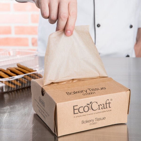 A person putting Bagcraft EcoCraft Bakery Tissue in a box.