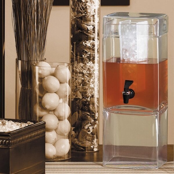 A Cal-Mil square glass beverage dispenser with an ice chamber on top.