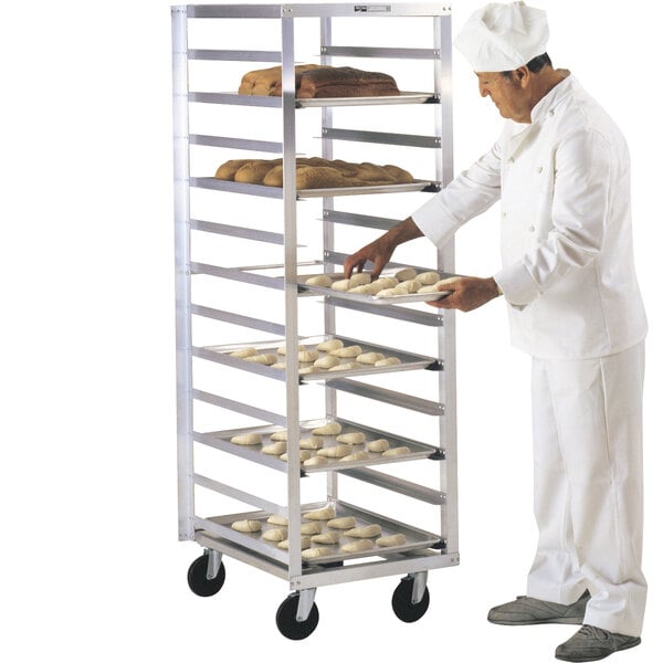 A chef in a white uniform putting food on a Metro sheet pan rack.
