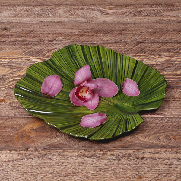 A green leaf shaped Elite Global Solutions melamine plate with pink flowers on it.
