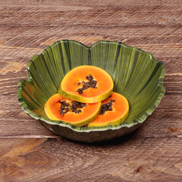 A Tropicana melamine bowl filled with papaya slices on a wood table.