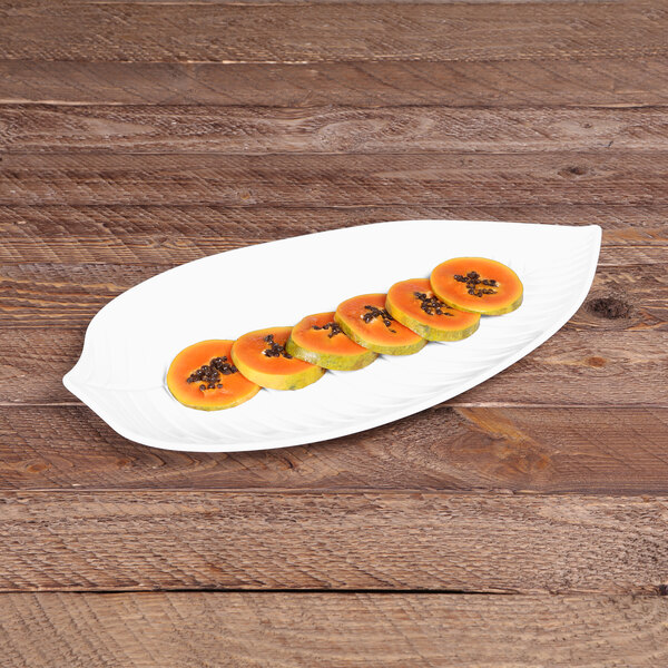 An Elite Global Solutions leaf-shaped white melamine platter with sliced papaya on it.
