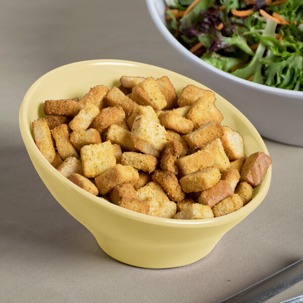 An Elite Global Solutions banana crepe melamine bowl filled with croutons on a table with a salad.