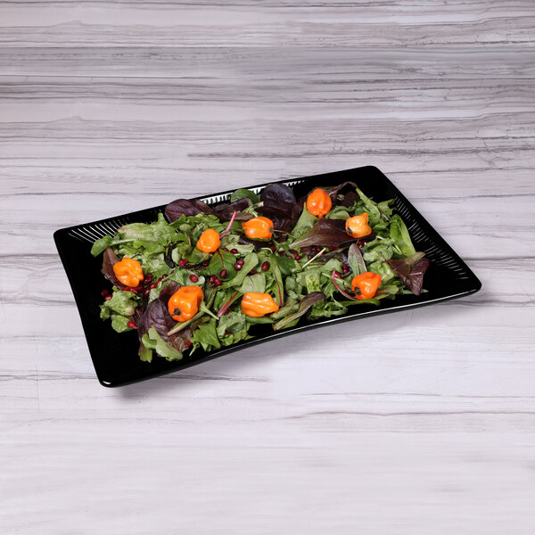 A black Elite Global Solutions rectangular melamine tray with a salad on it.