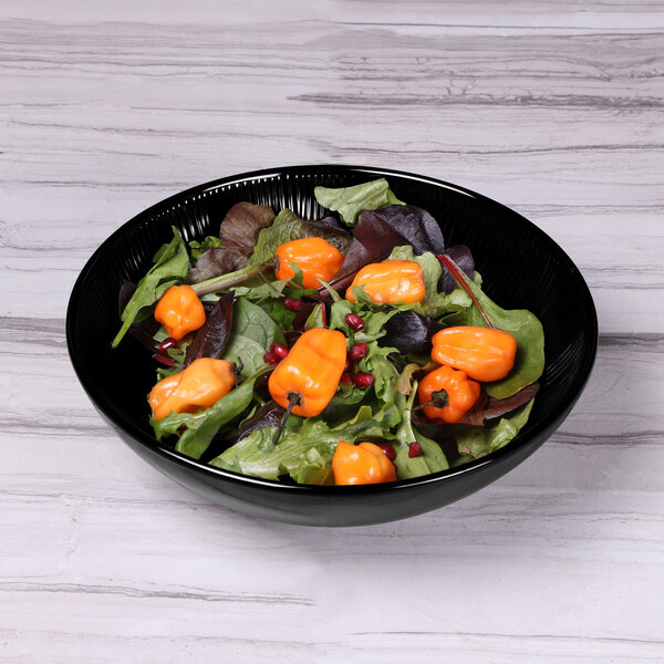 An Elite Global Solutions black melamine bowl filled with salad, including orange bell peppers.
